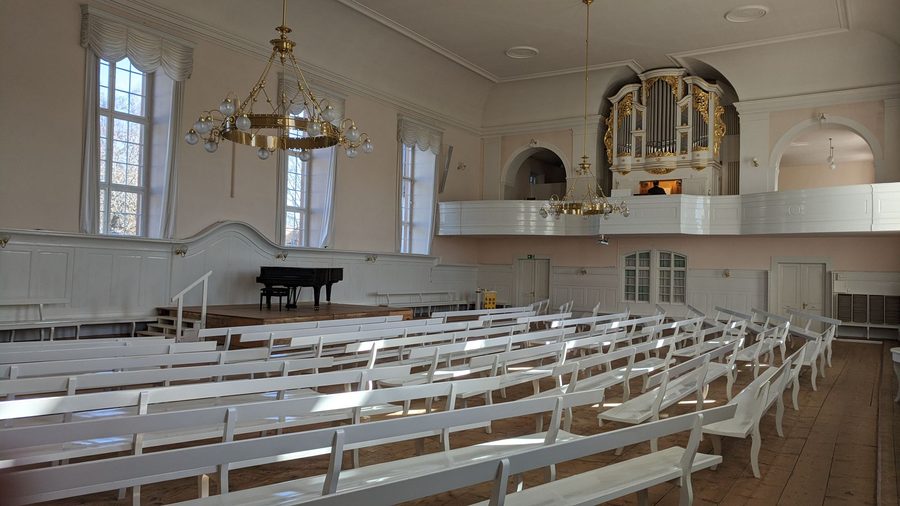 Kirchensaal der Herrnhuter Brüdergemeine in Königsfeld im Schwarzwald mit Sitzbänken, Kronleuchter, Klavier und Orgel